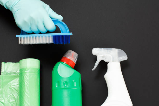 istock Woman's hand in a glove with a brush and cleaning set on the black background. 1299893003