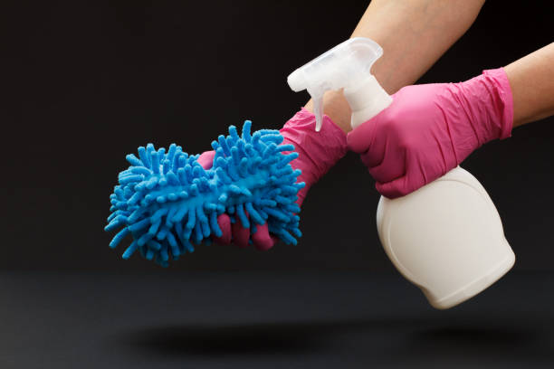 istock Hands with a bottle of washing liquid and a rag on a black background. 1299893111