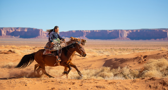 Navajo brothers galloping on horses in Arizona - USA
