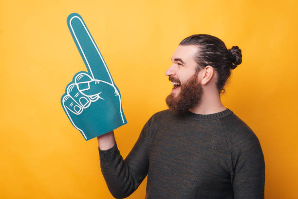 istock Bearded young man is holding a fan glove and screaming is looking away 1299896594