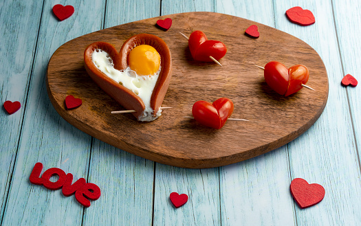 Romantic breakfast of sausages in the shape of a heart. Tomato hearts. Horizontal orientation