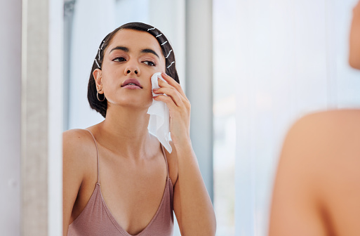 Shot of an attractive young woman cleansing her face with a wipe in front of the bathroom mirror