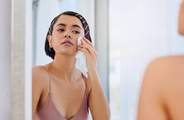 Leave no trace behind Shot of an attractive young woman cleansing her face with a wipe in front of the bathroom mirror woman washing face stock pictures, royalty-free photos & images