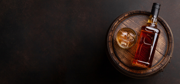 Botella de whisky escocés, vidrio y barril viejo photo