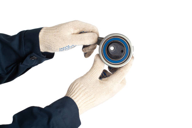 istock A car locksmith holds a spent old timing belt tensioner roller on a white background, isolate. Timing Belt Roller Replacement Concept 1299900785