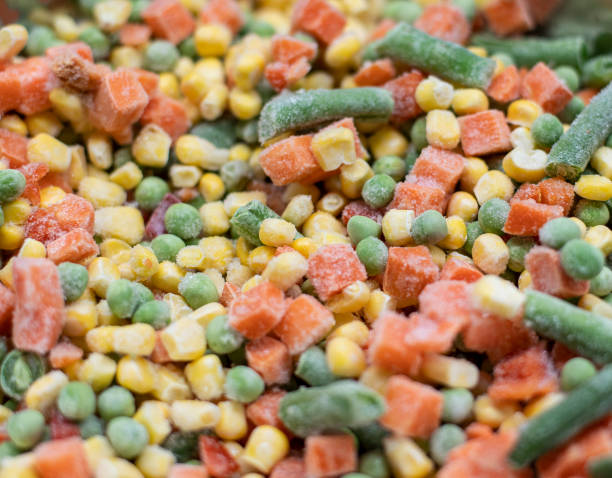 istock Colorful frosted vegetables carrot, corn and peas in heap 1299901835