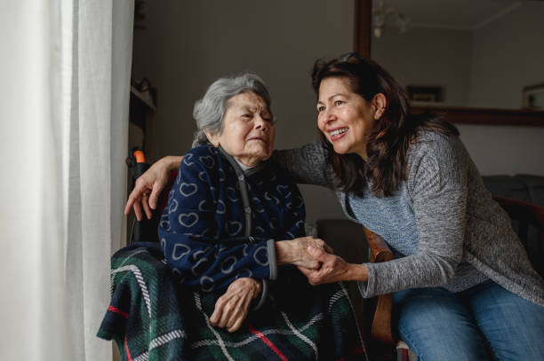 Old sick woman in wheelchair next to smiling daughter. Old sick woman in wheelchair next to smiling daughter. Third age, Home care concept. hispanic grandmother stock pictures, royalty-free photos & images