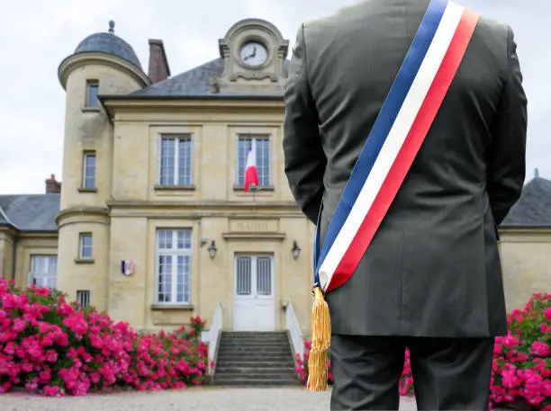 A mayor with his tricolor scarf in front of his town hall