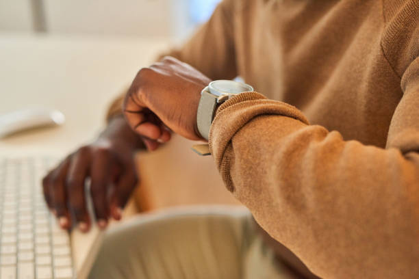 Closeup shpt of an unrecognisable businessman checking the time on his wristwatch in an office