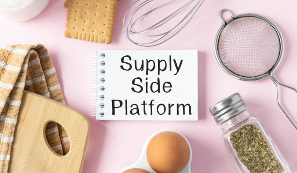 istock Cooking utensils and notepad on pink table and tablet with text SSP supply side platform. Culinary courses or blog. 1299915943