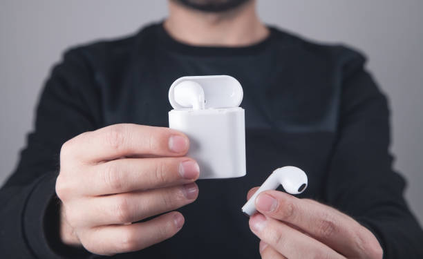 istock Caucasian man holding white wireless earphones. 1299919201