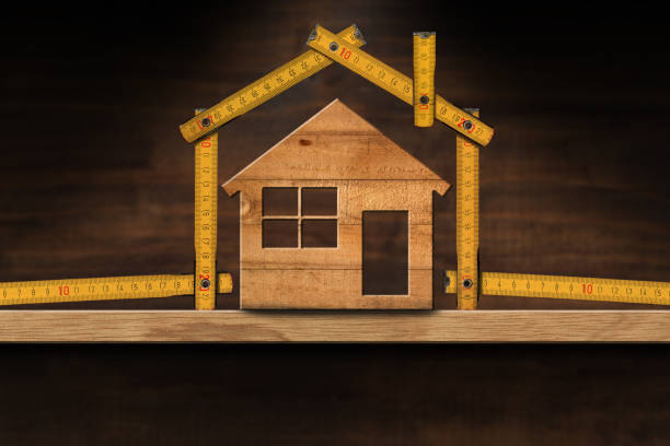 istock Folding Ruler House Shaped and Home Model on a Wooden Shelf 1299921528