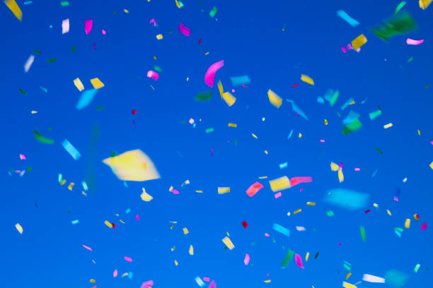 istock multicolored confetti on clear blue sky background. Concept of holiday backdrop 1299923409