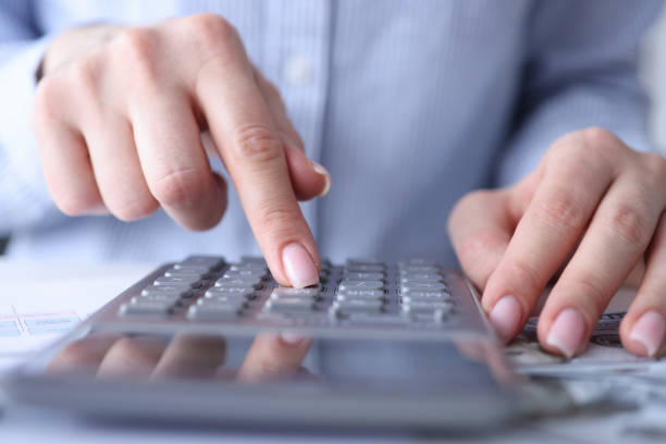 istock Female hands are counting on calculator at table closeup 1299923997