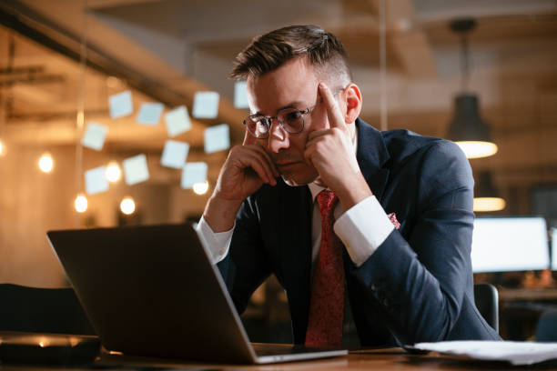 istock Exhausted businessman working with laptop at office. 1299925138