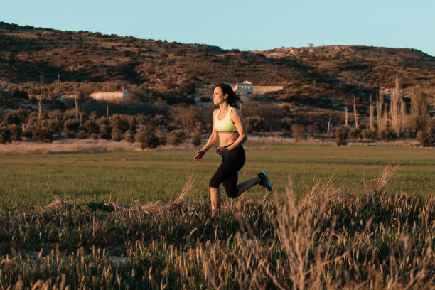 istock Woman runner running through the spring meadow. Workout in a nature. 1299925268