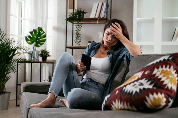 istock Sad woman sitting on the couch, using the phone 1299925355