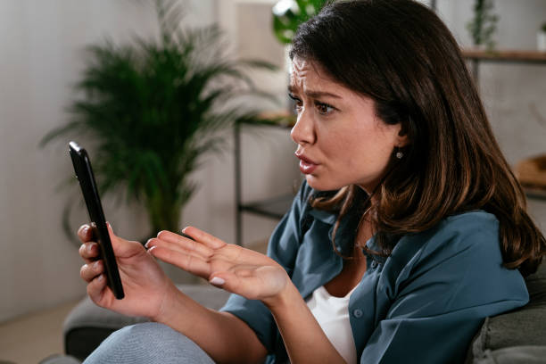 istock Sad woman sitting on the couch, using the phone 1299925417
