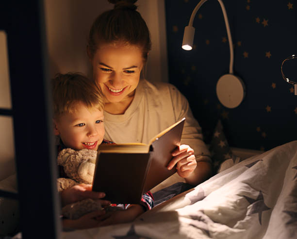 istock Cheerful mother and son cuddling and reading book 1299926276