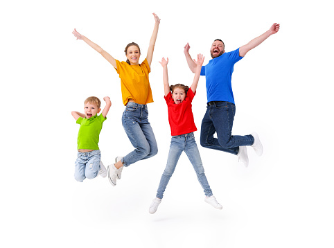 Positive family: couple and kids jumping with outstretched arms above ground in studio on white background while having fun and celebrating victory