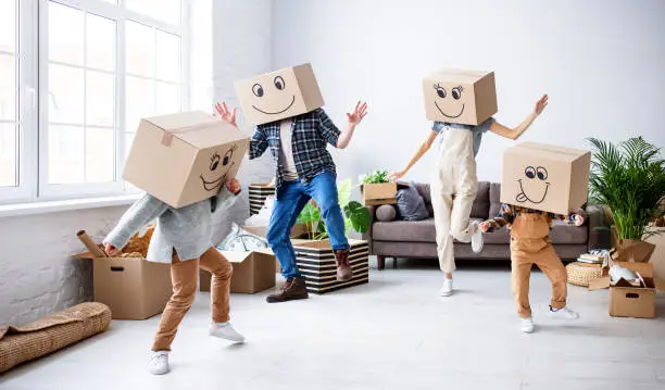 Photo of Cheerful family in carton boxes having fun during relocation