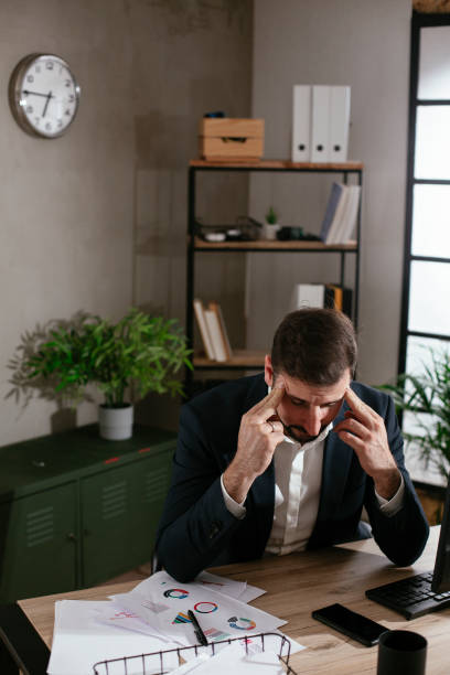 istock Exhausted businessman working with computer at office. 1299930866
