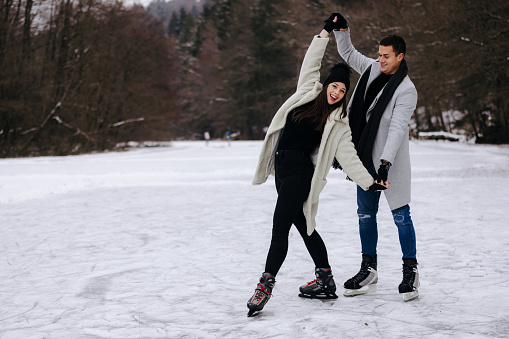 Young couple ice skating and dancing on a frozen lake