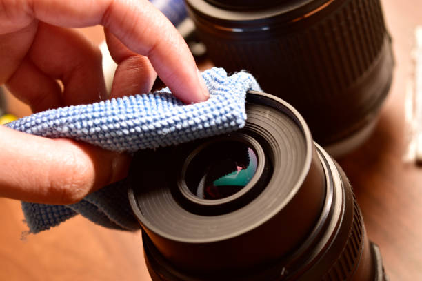 Cleaning camera lens from microfiber cloth stock photo