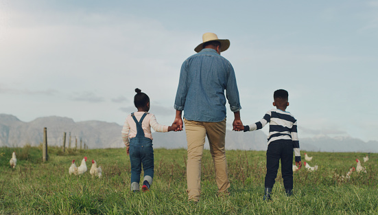 Rearview shot of a man and his two adorable children exploring a chicken farm