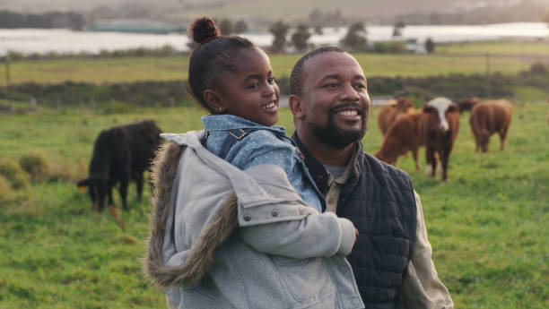 To nourish our families we must first nourish the land Shot of a mature man carrying his adorable daughter on a cow farm nourish stock pictures, royalty-free photos & images