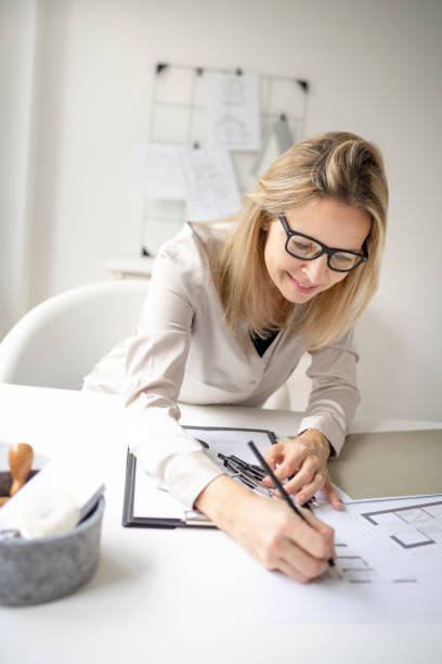 istock beautiful young, blond female architect is working in her office 1299938685