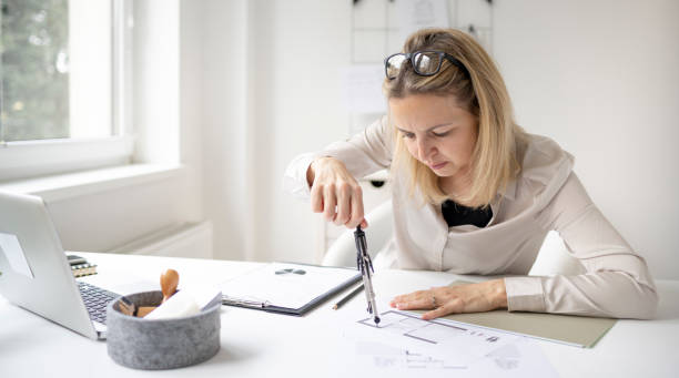 istock beautiful young, blond female architect is working in her office 1299938686