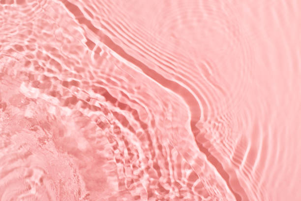 istock Transparent and clean pink water background with sunlight reflection 1299938888