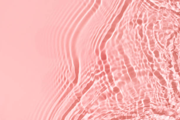 istock Transparent and clean pink water background with sunlight reflection 1299938899