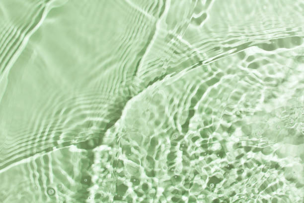 istock Transparent and clean green water background with sunlight reflection 1299939015