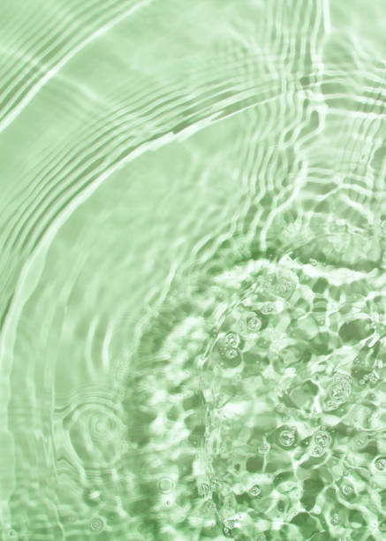 istock Transparent and clean green water background with sunlight reflection 1299939025