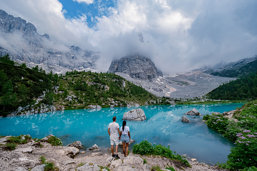 Beautiful Lake Sorapis Lago di Sorapis in Dolomites, popular travel destination in Italy. Blue green lake in Italian Dolomites. Couple hiking in the Dolomites Italy