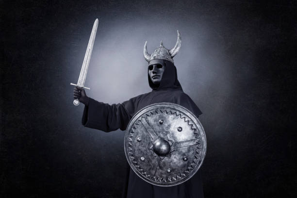 istock Scary figure with horned helmet, sword and round shield in the dark 1299941998