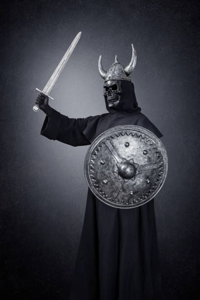 istock Skeleton warrior with horned helmet, sword and round shield in the dark 1299942068