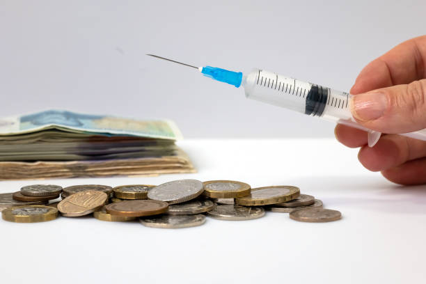 istock A syringe held in hand with money in the background 1299943912