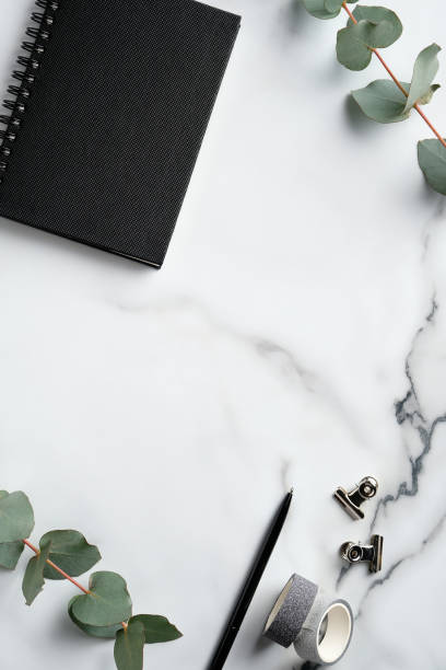 istock White marble office desk table with notebook, supplies, eucalyptus leaves. Top view with copy space, flat lay. Elegant feminine workspace. 1299944248