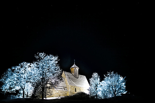 Old medieval church lit up on a starry winters night.