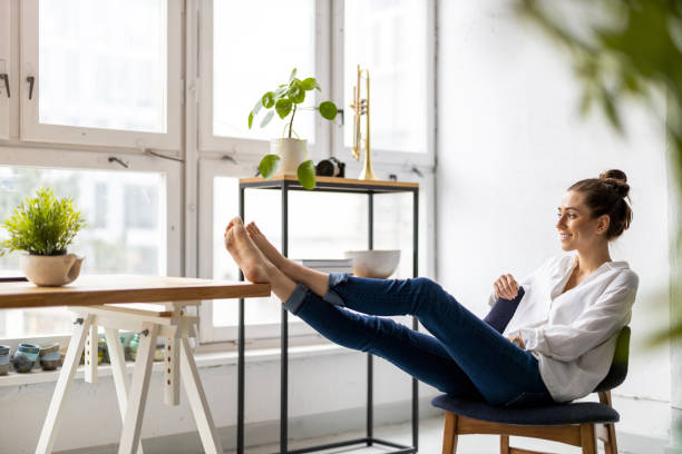 istock Young woman relaxing in office with her bare feet on desk 1299946537