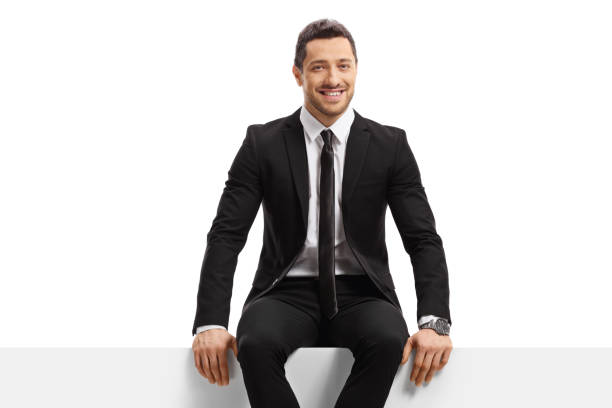 istock Businessman in a suit sitting on a panel and smiling 1299946752