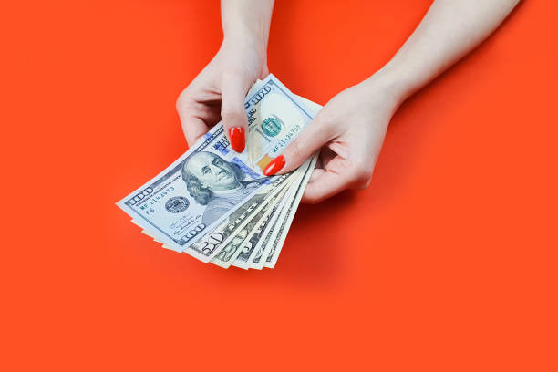 istock dollar bills in female hands with red manicure 1299947685