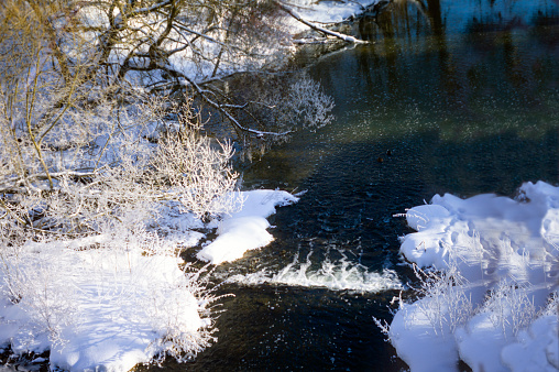 February sunny day shot of a river  and snowy banks with trees