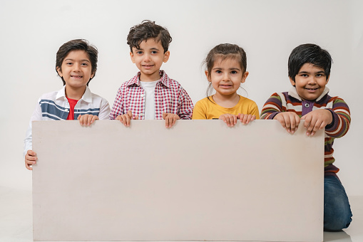 Children holding white board in studio lookin at the camera