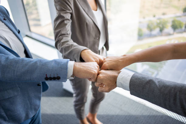 mani di quattro manager in pugno insieme per l'accordo - women standing fist success foto e immagini stock