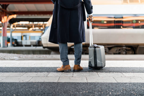 homme d’affaires attendant à la gare - valise à roulettes photos et images de collection