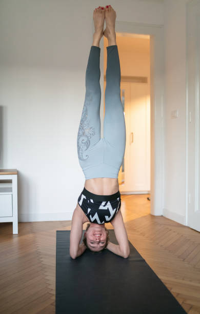 istock Woman practicing yoga at home in headstand pose 1299949797